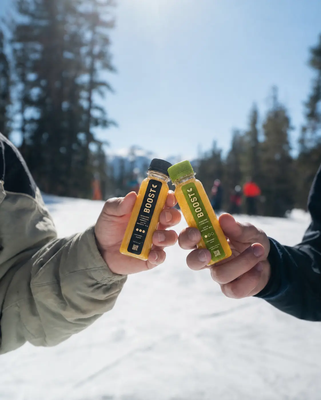 Duas mãos brindando com shots Boost Original e Suave na neve